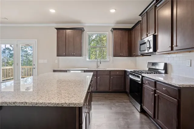 a kitchen with granite countertop stainless steel appliances a sink stove top oven and cabinets