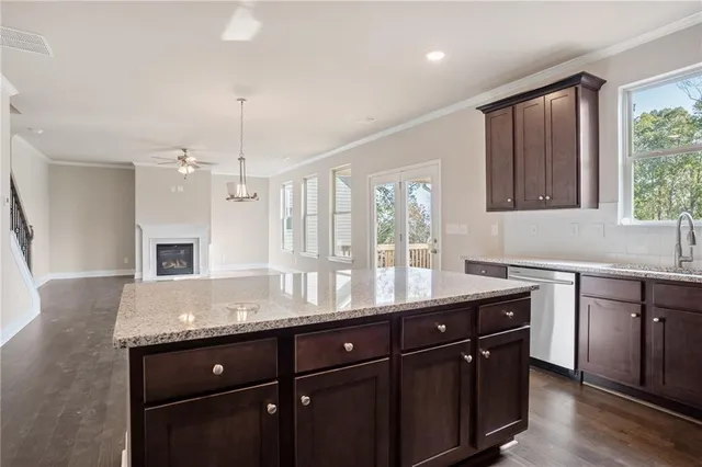 a kitchen with granite countertop cabinets a sink dishwasher and a stove with wooden floor