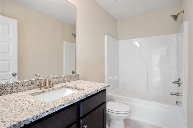 a bathroom with a granite countertop sink a toilet and shower