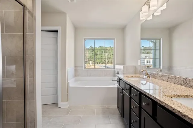 a bathroom with a granite countertop bathtub a sink and a window