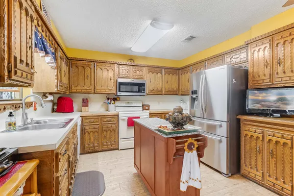 a kitchen with refrigerator a stove a sink dishwasher and wooden cabinets with wooden floor