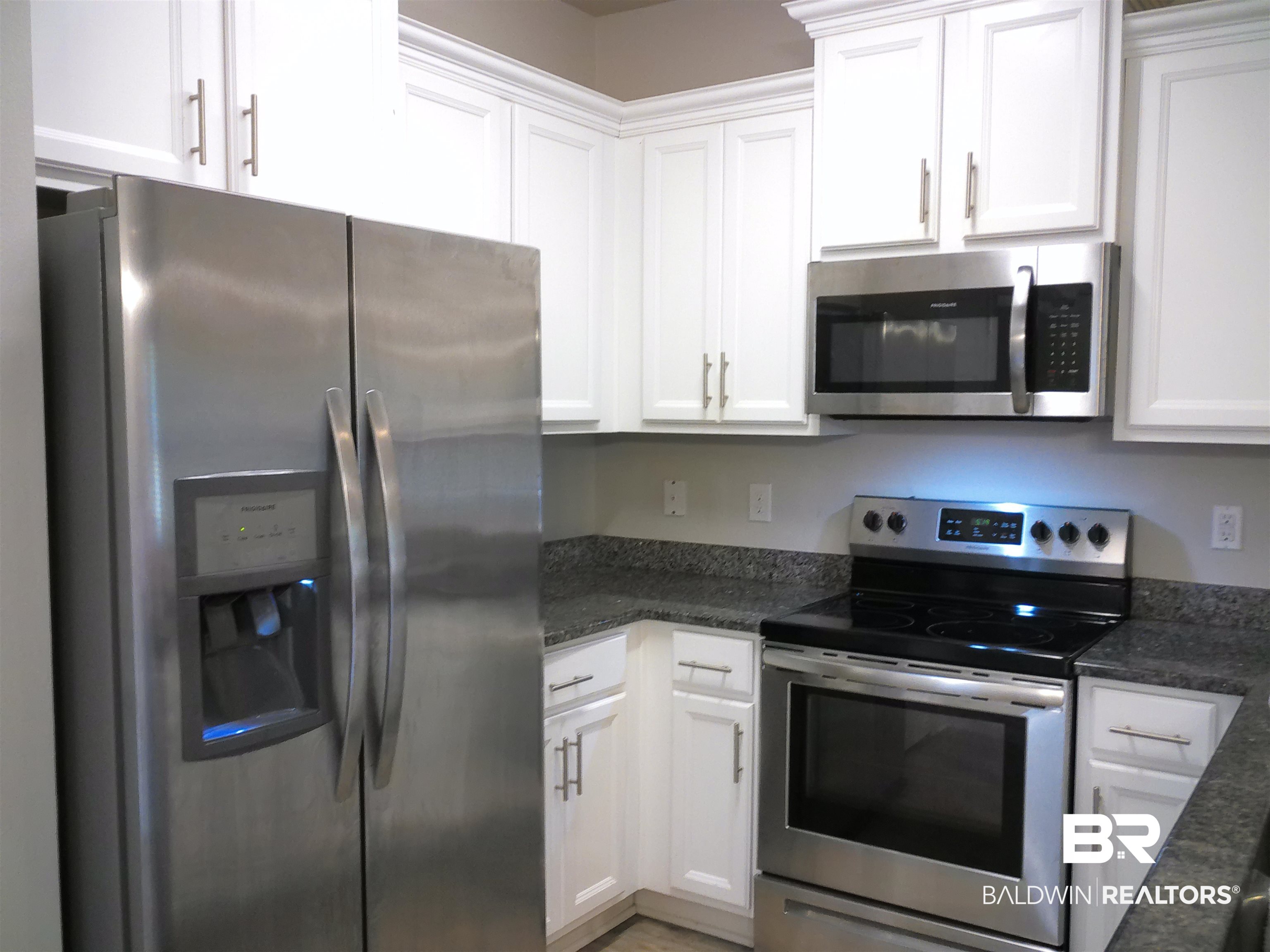 25806 Pollard Road, Unit 23 Daphne, AL 36526 - Photo 2 of 16 Kitchen featuring stainless steel appliances, white cabinets, and dark stone countertops