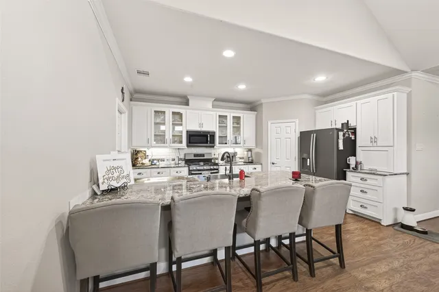 a kitchen with stainless steel appliances granite countertop a kitchen island hardwood floor sink stove dining table and chairs