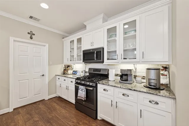 a kitchen with granite countertop white cabinets stainless steel appliances and a sink