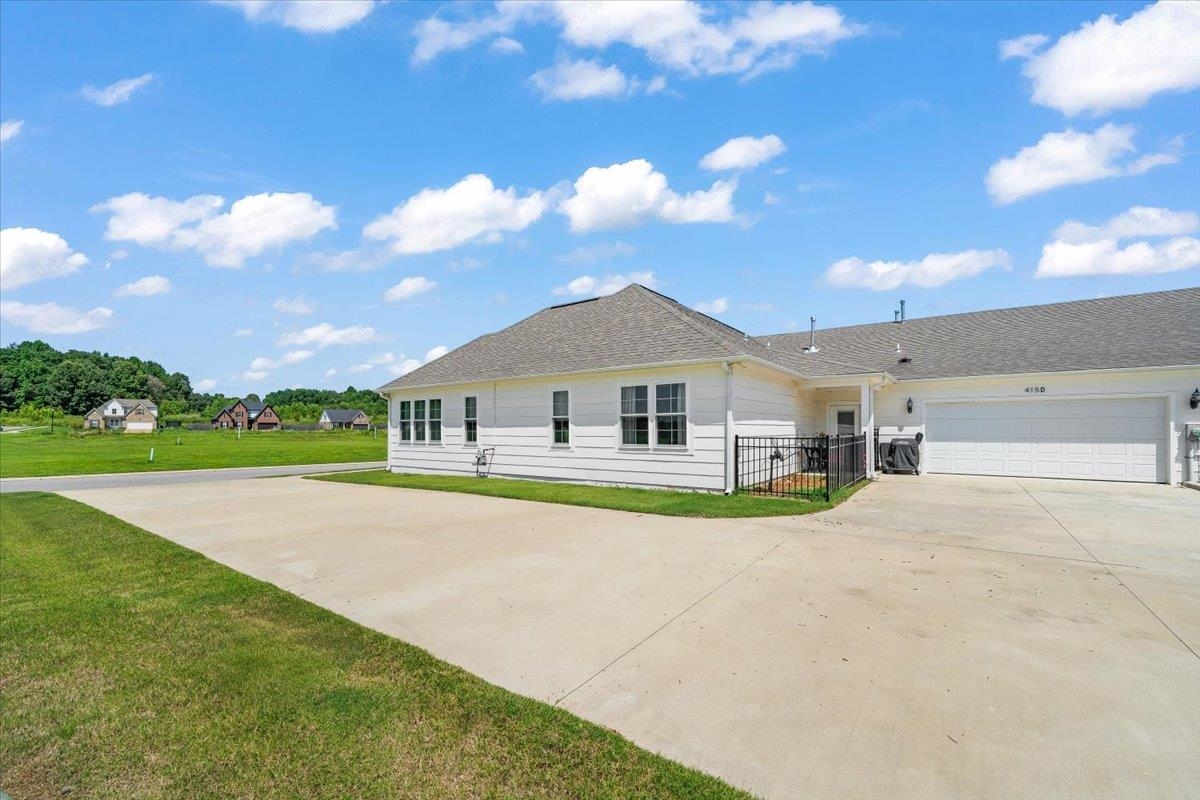 415 Abbey Road, Unit D Munford, TN 38058 - Photo 26 of 35 White siding exterior with multiple windows, a grey shingle roof, and a large concrete driveway