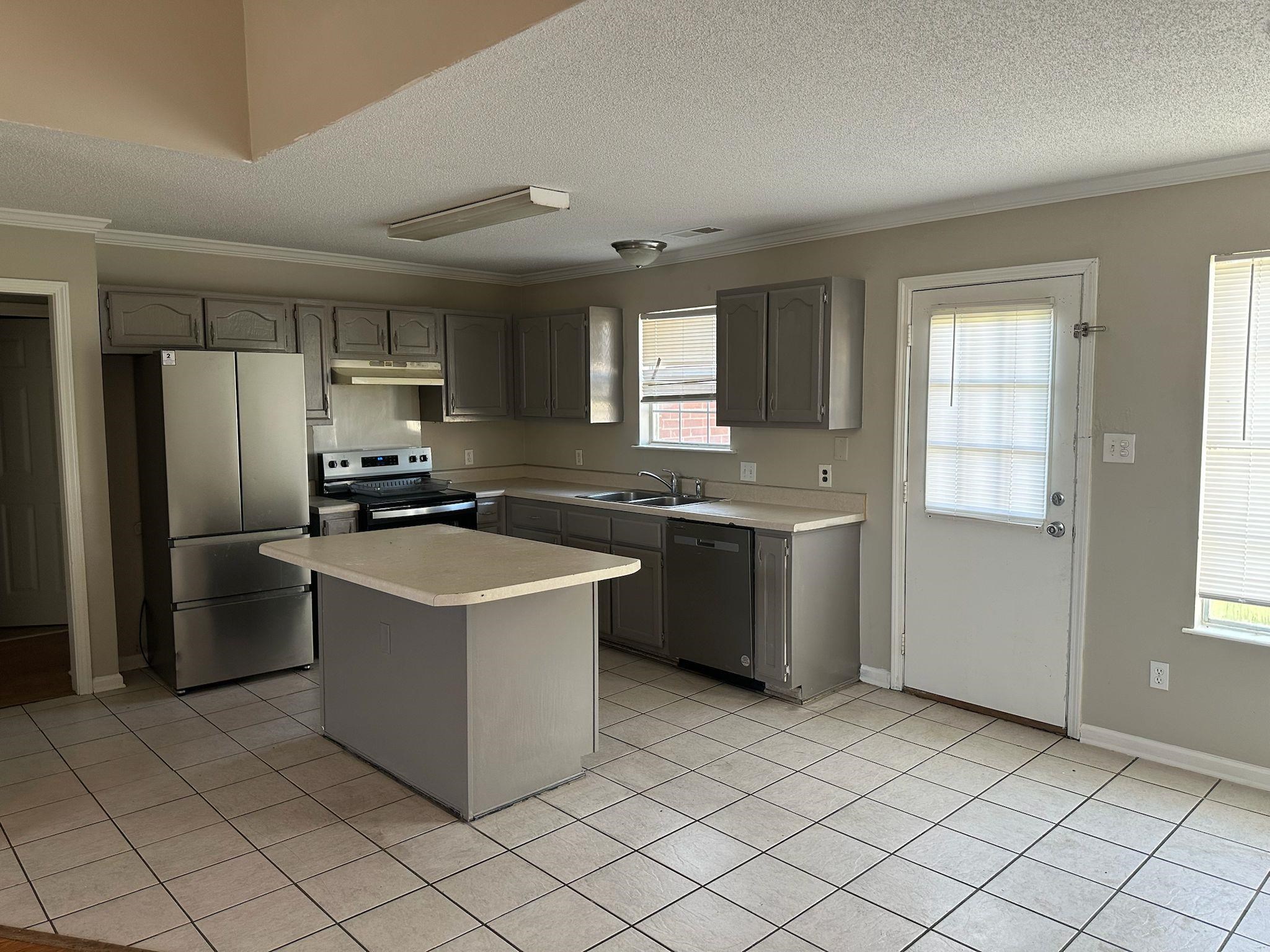 10007 Cameron Ridge Trail Memphis, TN 38016 - Photo 3 of 16 Kitchen with stainless steel appliances, light countertops, ornamental molding, a textured ceiling, and a center island