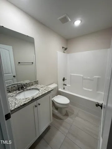 a bathroom with a granite countertop sink a toilet and a shower