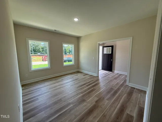 a view of an empty room with wooden floor and a window