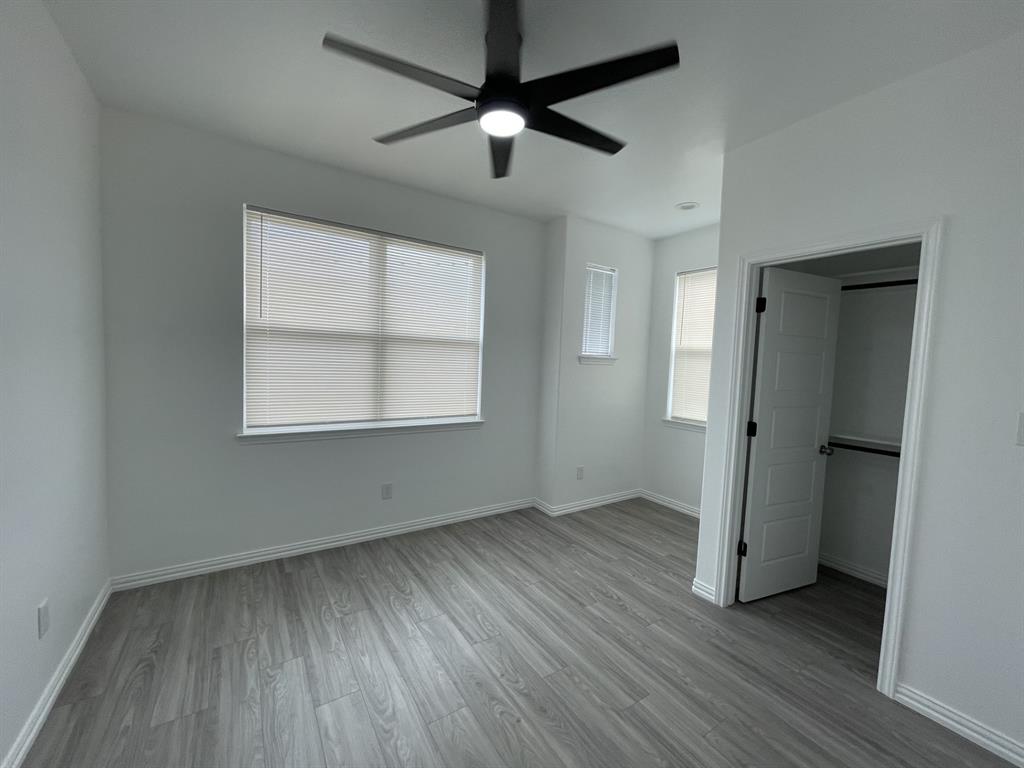 3309 Collin Street Fort Worth, TX 76119 - Photo 13 of 15 an empty room with wooden floor a ceiling fan and windows