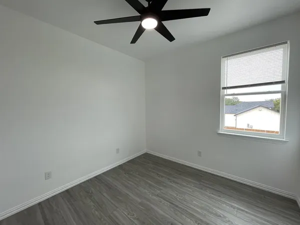 an empty room with a window and a ceiling fan