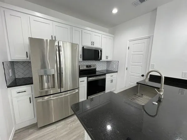 a kitchen with a refrigerator sink and cabinets