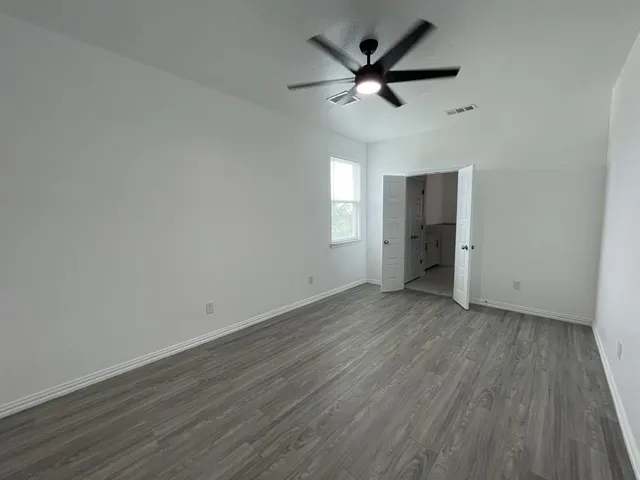 an empty room with wooden floor and a ceiling fan