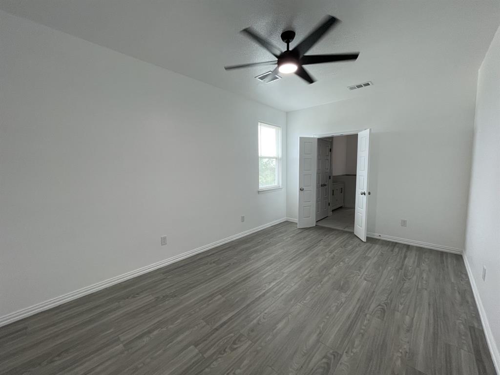 3309 Collin Street Fort Worth, TX 76119 - Photo 8 of 15 an empty room with wooden floor and a ceiling fan