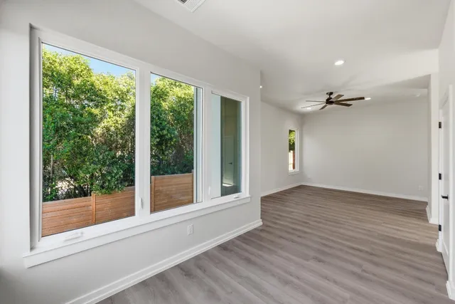 a view of an empty room with wooden floor and a window