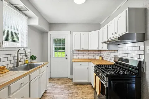 a kitchen with granite countertop a sink stove and cabinets