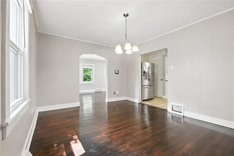 a view of an empty room with window and wooden floor