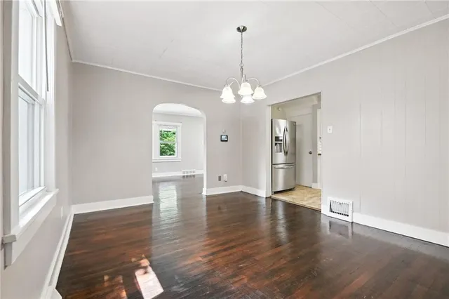 a view of an empty room with window and wooden floor