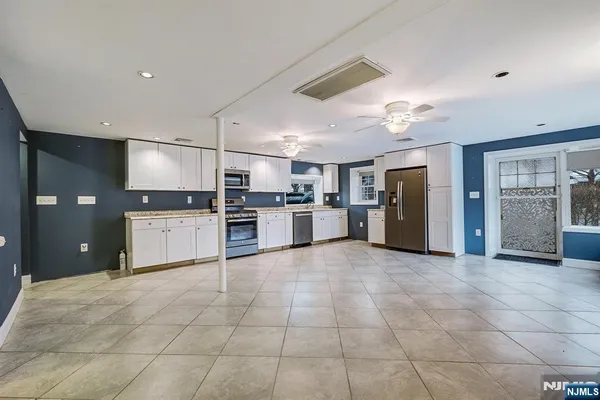 a large white kitchen with a stove a sink cabinets and a refrigerator