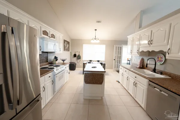 a large white kitchen with sink stove and refrigerator