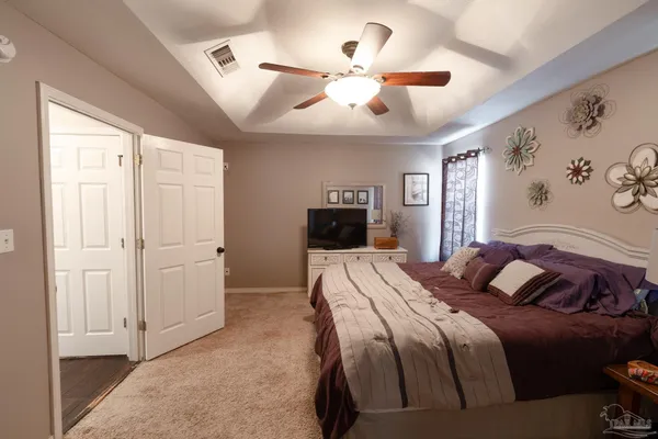 a bedroom with a large bed a flat tv screen and dresser