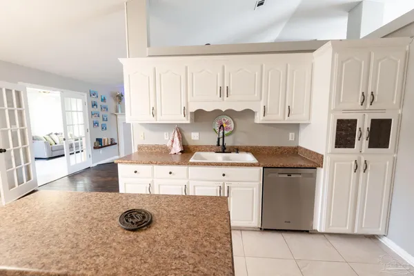 a large kitchen with a refrigerator a sink dishwasher a stove and white cabinets with wooden floor