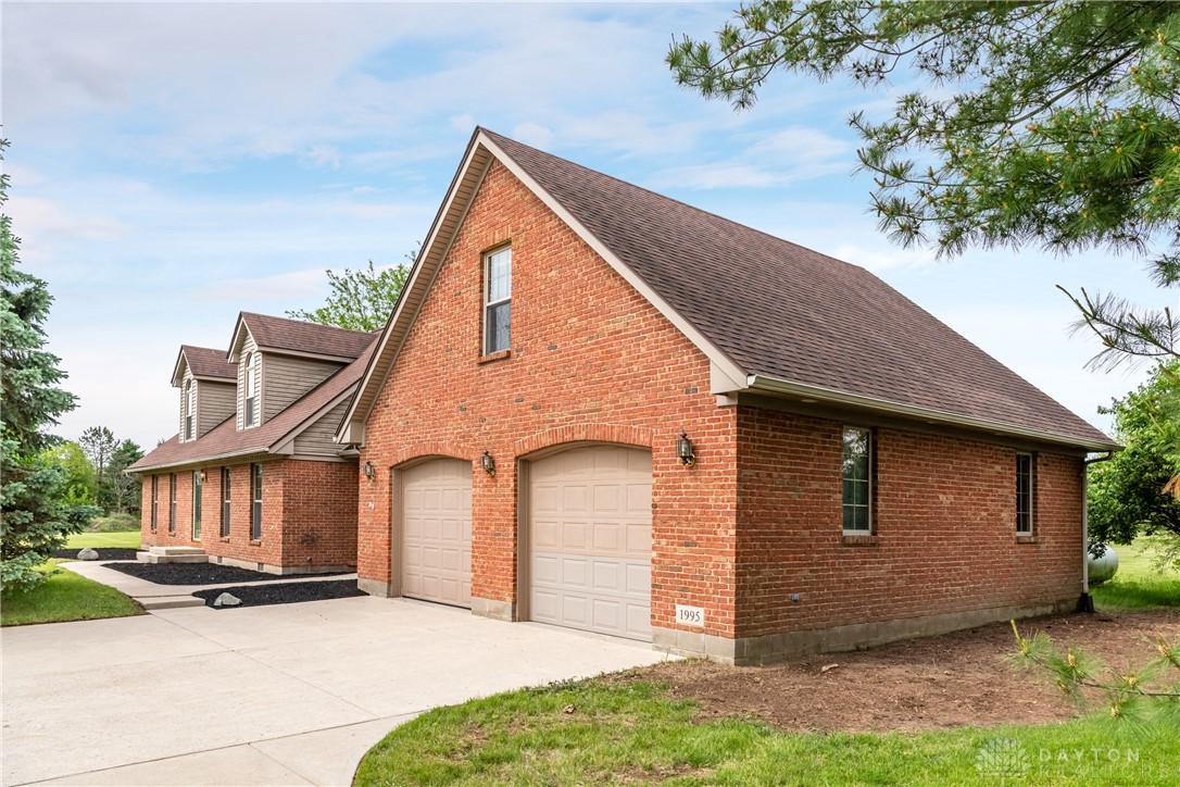 9981 Ridge Acres Lane Englewood, OH 45322 - Photo 1 of 73 This classic brick residence features an attached garage with a concrete driveway and lush green surroundings.