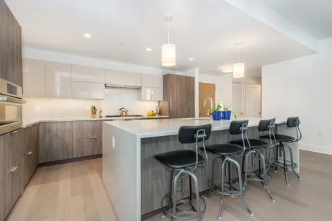 a kitchen with kitchen island granite countertop a sink cabinets and dining table