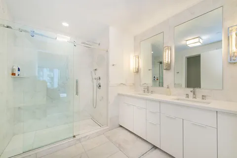 a bathroom with a double vanity sink mirror and shower