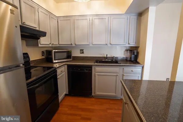 a kitchen with granite countertop a sink a stove and refrigerator