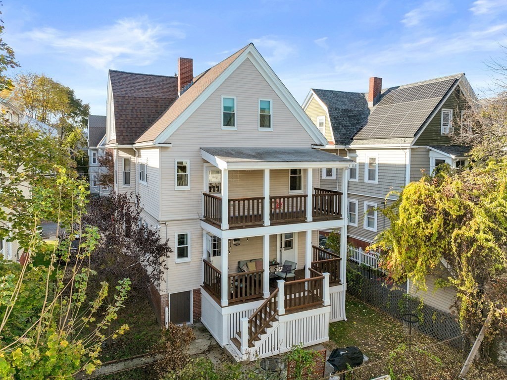 89 Bromfield Road Somerville, MA 02144 - Photo 40 of 41 a view of a white house next to a yard with plants and large trees