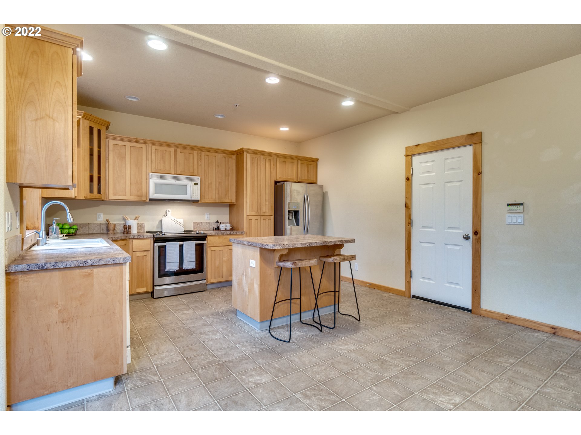 640 Southwest Trout Court Camas, WA 98607 - Photo 6 of 32 a open kitchen with kitchen island granite countertop wooden cabinets a sink a stove a chimney and a refrigerator