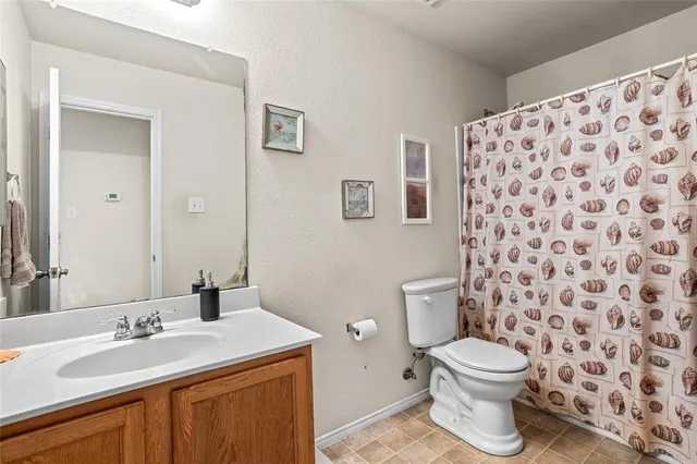 a bathroom with a granite countertop toilet a sink a mirror and a shower