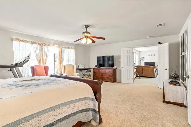 a bedroom with a bed a couch and a flat tv screen on dresser