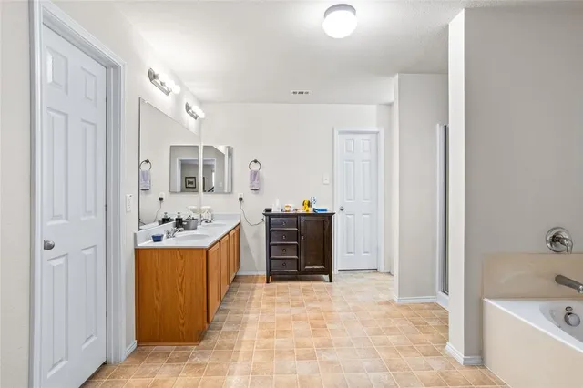 a large bathroom with a tub sink and mirror