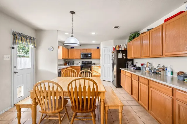 a kitchen with stainless steel appliances granite countertop a refrigerator a stove top oven a sink dishwasher and white cabinets with wooden floor