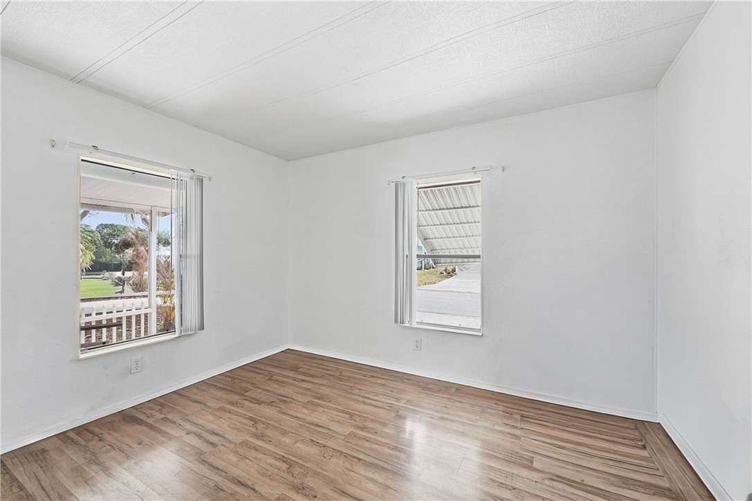 566 Dolphin Circle Sebastian, FL 32976 - Photo 18 of 36 an empty room with wooden floor and windows