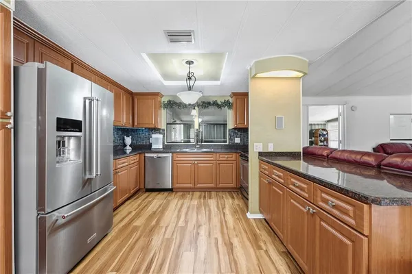 a kitchen with stainless steel appliances granite countertop a refrigerator a stove and a sink