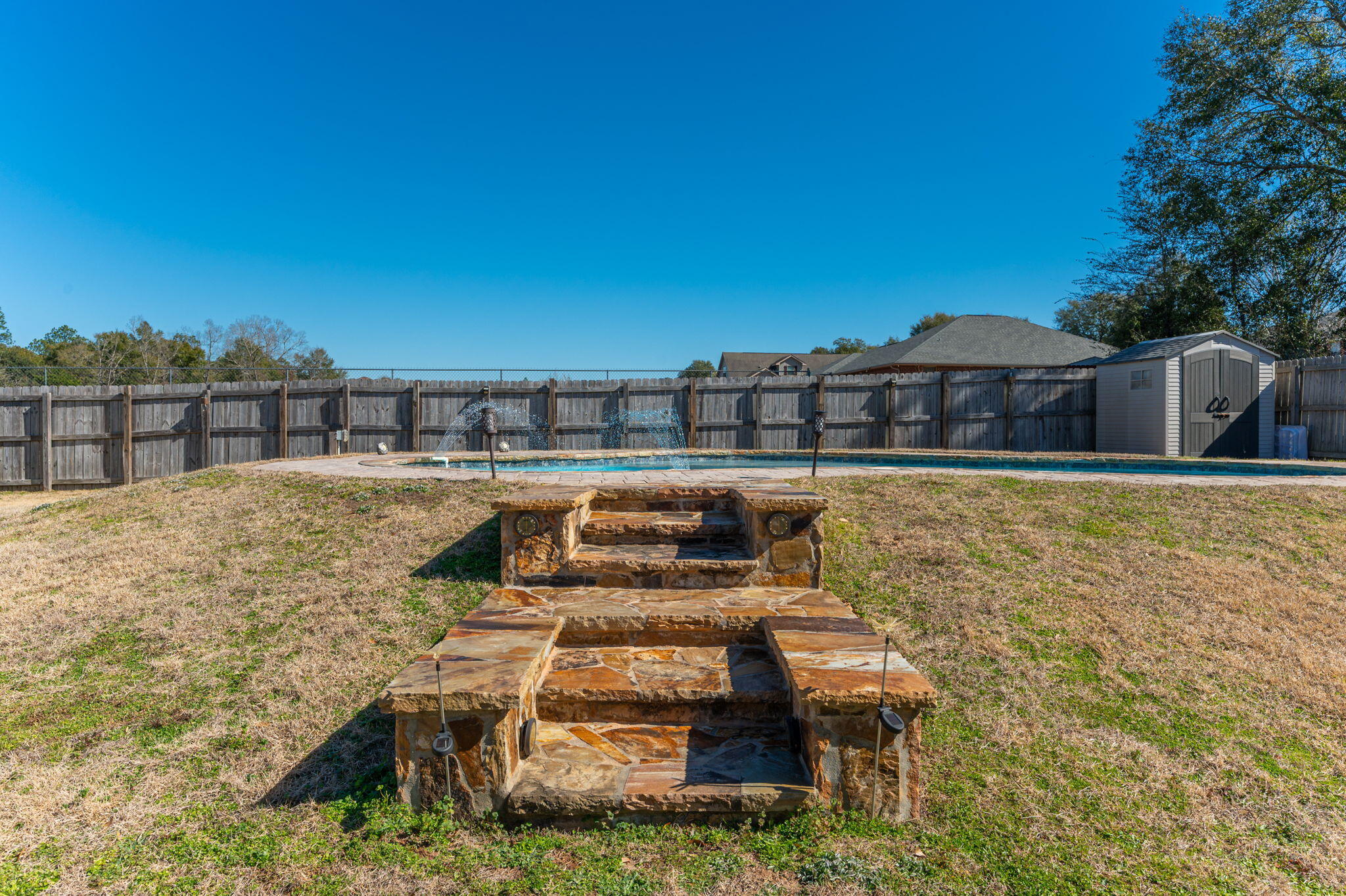 2342 Genevieve Way Crestview, FL 32536 - Photo 37 of 41 a roof deck with table and chairs under an umbrella with large trees