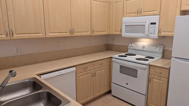 a kitchen with granite countertop white cabinets and white appliances