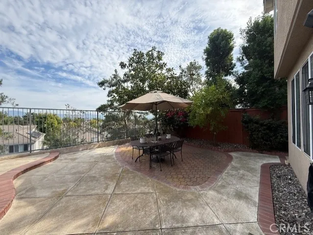 a view of a table and chairs under an umbrella in backyard of house
