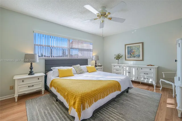 a bedroom with a bed a dresser and wooden floor