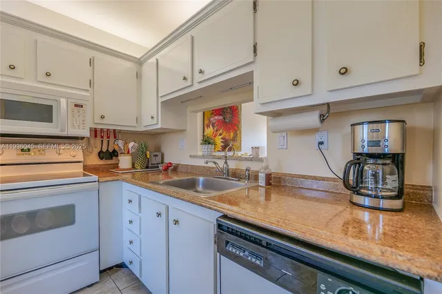 a kitchen with stainless steel appliances granite countertop a sink stove and white cabinets