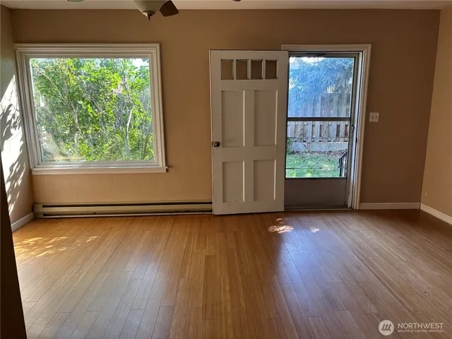 an empty room with wooden floor and windows