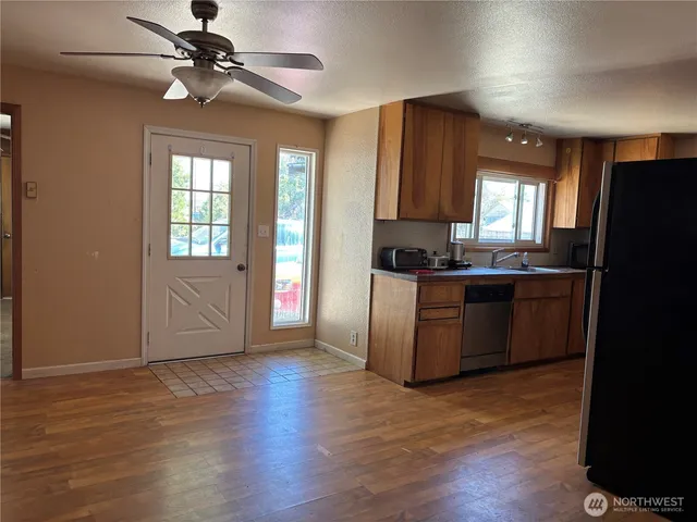 a kitchen with stainless steel appliances granite countertop a refrigerator a sink dishwasher a stove with wooden floor and cabinets