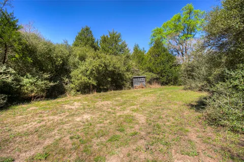a view of a wooden house with large trees