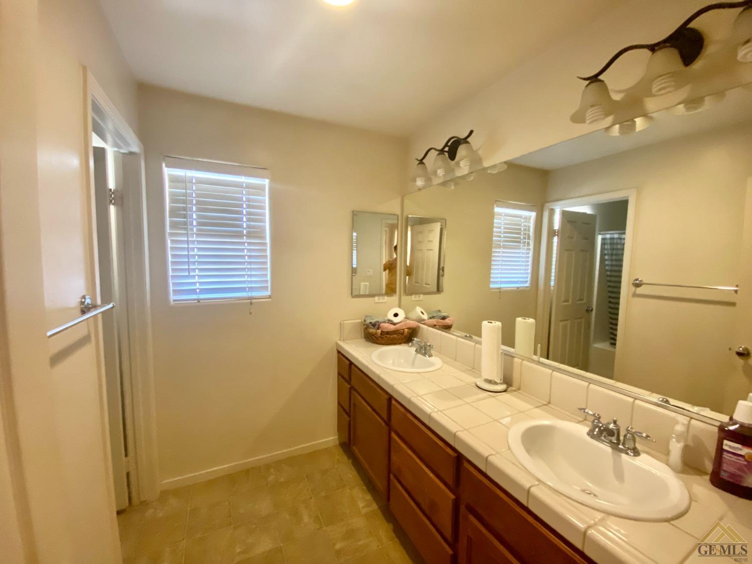 Undisclosed Address Bakersfield, CA 93312 - Photo 26 of 38 a spacious bathroom with a double vanity sink a mirror and a shower