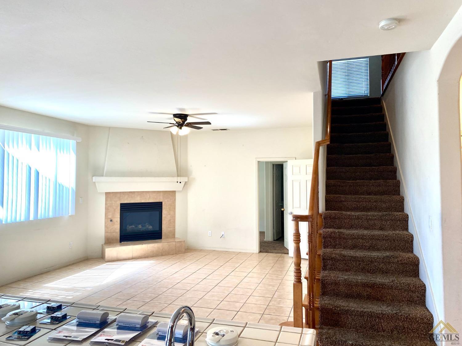 Undisclosed Address Bakersfield, CA 93312 - Photo 4 of 38 a view of a livingroom with a fireplace a ceiling fan and windows