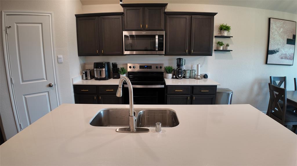 1215 Rustic Vw Lane Denton, TX 76207 - Photo 8 of 25 a kitchen with stainless steel appliances a stove a microwave a sink a refrigerator and cabinets