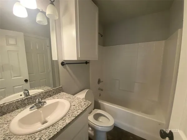 a bathroom with a granite countertop toilet sink and mirror