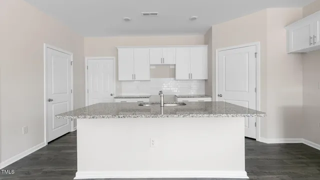 a large white kitchen with a granite counter tops and a sink